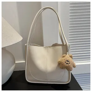 Close-up of minimalist cream PU leather tote bag with a cute plush star charm