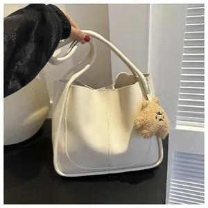 Detail of cream PU leather tote bag with vertical stitching and cute plush bear charm