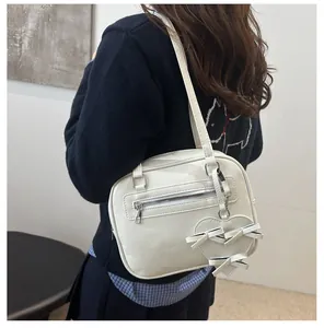 Bolso de hombro en cuero PU blanco crema con colgante de corazón mostrado en modelo