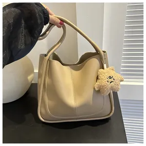Detail of beige PU leather tote bag featuring a central seam and star plush charm