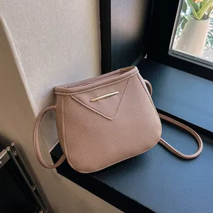 Chic dusty pink crossbody bag in pebbled faux leather with gold trim on V-shaped flap