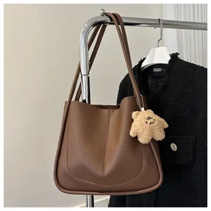 Detail of dark brown faux leather tote bag with curved stitching and star plush charm