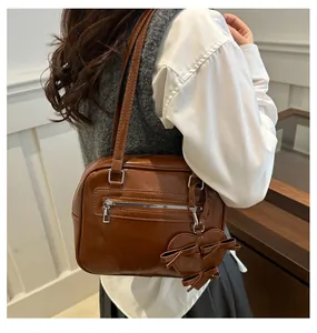 Detalle de bolso bandolera marrón vintage con cremallera y colgante de corazón