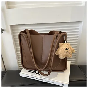 Detailed close-up of brown PU leather tote bag with decorative stitching and plush bear charm