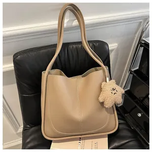 Detail of khaki PU leather tote bag with plush star pendant on a black chair