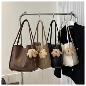 Four minimalist PU leather tote bags in various colors hanging on a silver metal rack