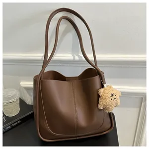 Brown faux leather tote bag detail with vertical stitching and star-shaped plush charm