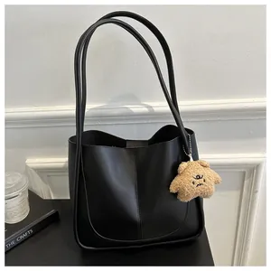 Close-up of black PU leather tote bag with stitch detail and plush star pendant charm
