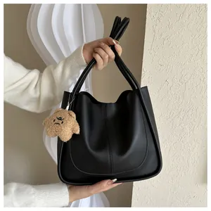 Detail of a black leather tote bag with U-shaped stitching and a cute plush star charm