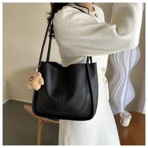 Detail of black matte PU tote bag with central stitching and cute plush bear charm