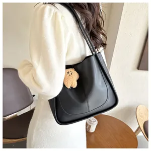 Detail of black faux leather tote bag with U-shaped stitching and plush star charm