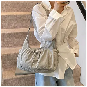 Detail van grijze nylon crossbodytas met trekkoord en geplooide zakken aan de kant
