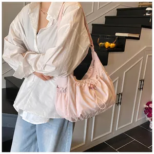 Detailweergave van een lichtroze gewatteerde crossbodytas met trekkoord op model
