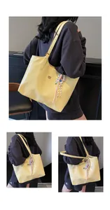 Detail view of bright yellow glossy leather tote bag with stylish charm and logo