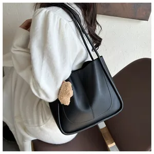 Detailed view of black PU leather tote bag with U-shaped stitching and cute bear pendant