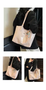 Macro shot of light pink patent leather tote bag showing metallic logo and charm