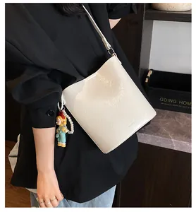 Detail of ivory leather bucket bag with cute doll charm and pearl chain accent