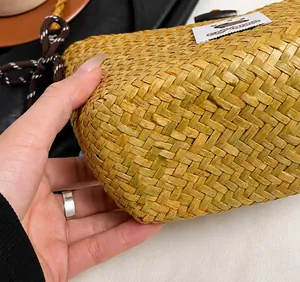 Close-up of woven straw bucket bag with Capybara label and precision stitching details