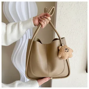 Detail of khaki PU leather tote bag with vertical stitching and brown teddy bear charm