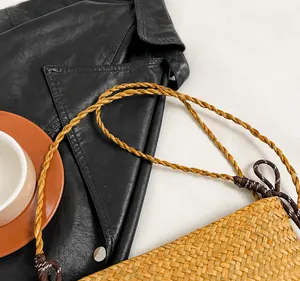 Detail of woven straw bucket bag showing handmade braided strap and fine craftsmanship