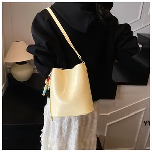 Detail of yellow bucket bag with adjustable strap and colorful bead charm decoration