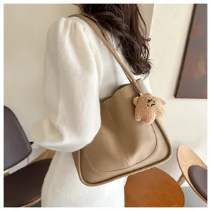 Detail of a beige PU leather tote bag with vertical stitching and star plush charm