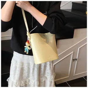 Detail view of cream shoulder bucket bag with pearl chain and cartoon charms on model
