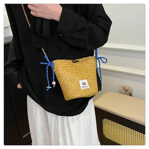 Detail of straw bucket bag with blue braided strap and cute cartoon capybara patch