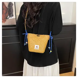 Detail of handmade straw bucket bag featuring blue braided rope and Capybara patch