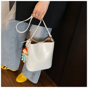 Detail of white glossy bucket bag featuring a cute cartoon doll pendant and beads