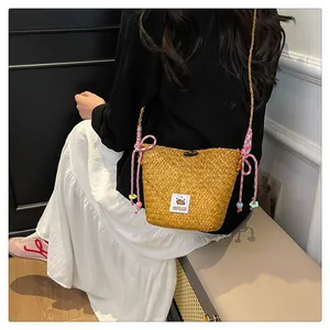 Detail of hand-woven straw bucket bag with cute capybara patch and colorful cotton rope strap