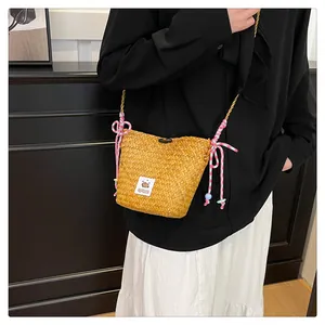 Detail view of handmade straw bucket bag featuring pink cotton rope bow and capybara patch