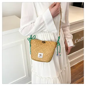 Close-up of woven straw bucket bag featuring a Capybara patch and green beaded strap