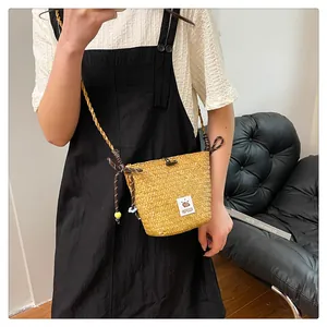 Detail of handwoven straw bucket bag with cute bear patch and floral bead strap