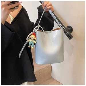 Close-up of light blue wrinkled bucket bag with pearl charm and cute doll accessory