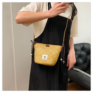 Detail of hand-woven straw crossbody bag with Capybara patch and beaded drawstring strap