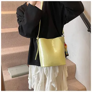 Macro detail of glossy yellow bucket bag with retro wrinkled texture and side charms