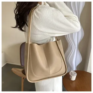 Detailed back view of a beige PU leather tote bag worn by a model in a minimal room