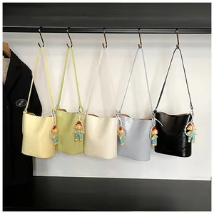 Detail of five colorful pleated bucket bags with cute pearl doll pendants on display