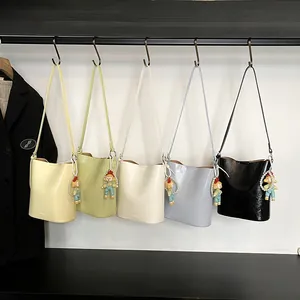 Minimalist glossy bucket bag for women available in five colors with cute doll pendant