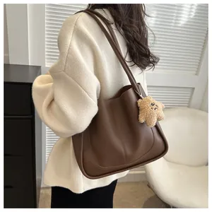 Detail of dark brown tote bag featuring slender shoulder straps and plush star pendant