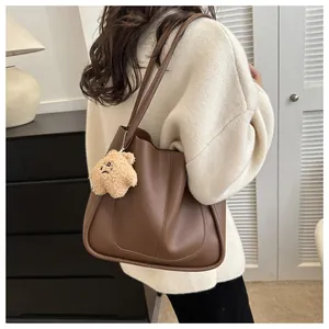 Close-up of deep brown tote bag with matte texture and cute yellow teddy bear charm