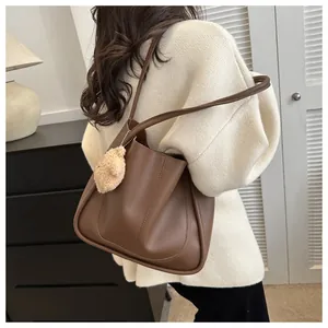 Detail of soft dark brown leather shoulder bag with a cute plush bear charm accessory