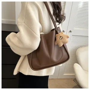Detail of dark brown leather tote bag with plush star pendant and minimalist stitching
