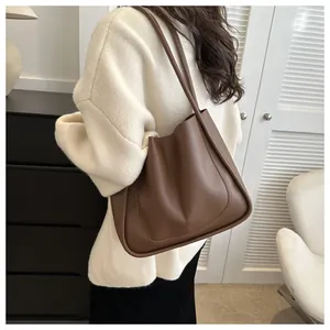 Dark brown leather tote bag side view with decorative stitching shown on a model
