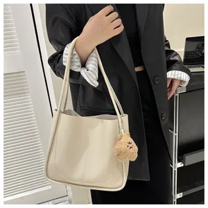 Close-up of cream PU leather tote bag with vertical stitching and plush bear charm