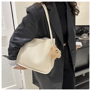 Detail of cream PU leather tote bag with a cute brown plush star charm on shoulder strap