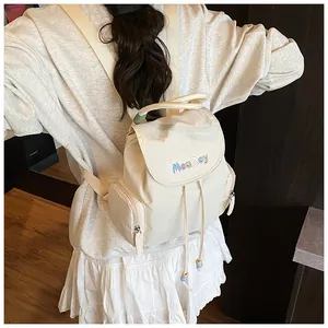Détail d'un sac à dos en nylon beige crème avec broderie MeaRey colorée et cordon serrage