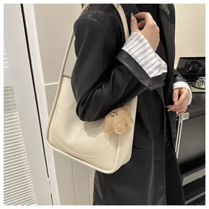Detail of beige PU leather tote bag with cute brown plush bear charm accessory