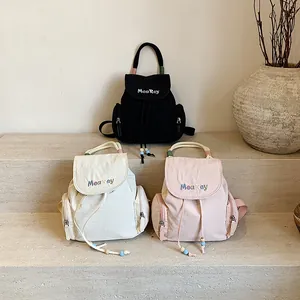 Sacs à dos en nylon noir, beige et rose avec détails de cordes sur marches en pierre